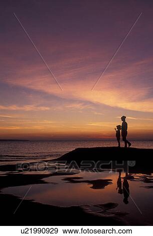 Stock Photo -  silhouette, sunset, sunrise, Pictured Rocks, Lake Superior, Upper Peninsula, U. P Michigan, Mother and daughter standing on the edge of Lake Superior at sunset at Pictured Rocks National Lakeshore in Munising in the state of Michigan.. Fotosearch