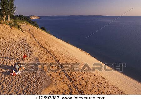Sleeping Bear Dunes, sand dune, Michigan, Lake Michigan, People sitting on the edge of a steep sand dune (a perched dune) along Lake Michigan at Sleeping Bear Dunes National Lakeshore in the state of Michigan. View Large Photo Image Stock Photo - Sleeping Bear Dunes, sand dune, Michigan, Lake Michigan, People sitting on the edge of a steep sand dune (a perched dune) along Lake Michigan at Sleeping Bear Dunes National Lakeshore in the state of Michigan.. Fotosearch