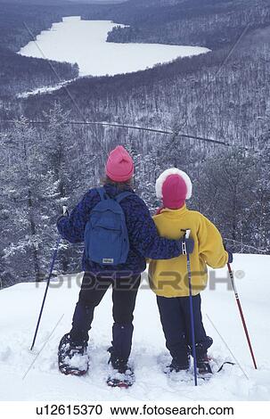 Stock Image -  snowshoeing, Vermont, VT, Mother and daughter snowshoeing on Owl's Head overlooking the frozen Kettle Pond in Groton State Forest in winter.. Fotosearch