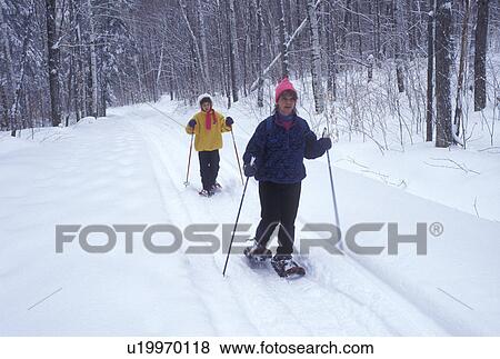 Stock Photo -  snowshoeing, Vermont, VT, Mother and daughter snowshoeing on a snow-covered trail in Groton State Forest in winter.. Fotosearch