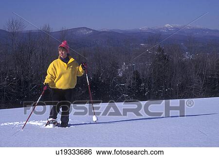 Stock Photograph -  snowshoeing, winter, Vermont, A Woman snowshoeing on a snow covered field on a winter day in Montpelier in Washington County in the state of Vermont.. Fotosearch