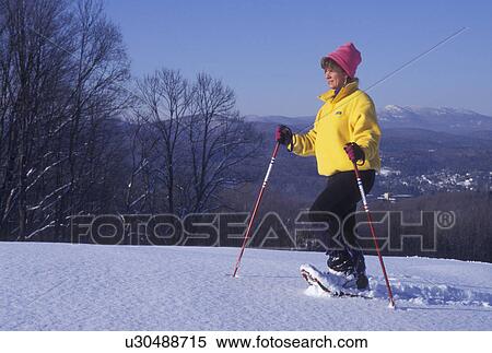 snowshoeing, winter, Vermont, A woman wearing a yellow jacket and pink hat snowshoes on snow covered field on a winter day in Montpelier in Washington County in the state of Vermont. View Large Photo Image Stock Photography - snowshoeing, winter, Vermont, A woman wearing a yellow jacket and pink hat snowshoes on snow covered field on a winter day in Montpelier in Washington County in the state of Vermont.. Fotosearch