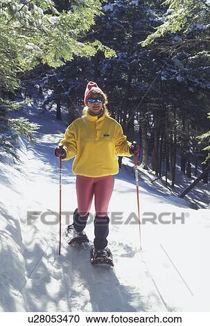Stock Image -  snowshoeing, winter, Vermont, VT, Woman snowshoeing on a snow-covered trail in winter in Montpelier.. Fotosearch