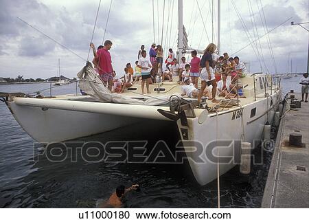 Stock Image -  St. Martin, Caribbean, Marigot, catamaran, Caribbean Islands, Tourist aboard a catamaran docked at the harbor in Marigot the French capital of the island of Saint Martin (french part).. Fotosearch
