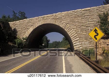 Stock Image -  stone bridge, road, arch, Acadia National Park, Maine, Arched stone bridge over a two lane road in Acadia Nat'l Park in the state of Maine.. Fotosearch