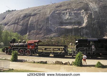 Stock Photo -  Stone Mountain, train, Atlanta, Stone Mountain Park, Georgia, Stone Mountain Railroad train crosses in front of The Confederate Memorial Carving on Stone Mt the massive dome of granite rock, in Georgia's Stone Mountain Park near Atlanta in the state of G. Fotosearch