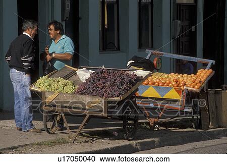 Stock Image -  street market, fruits, Chile, Chiloe Island, A street vendor selling fresh produce to a man in Castro on Chiloe Island in Chile.. Fotosearch