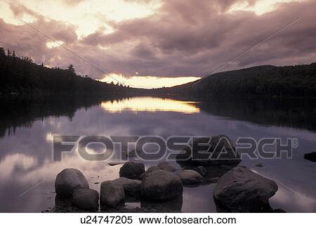 sunset, lake, Vermont, Clouds reflect in the calm waters of Kettle Pond at sunset with boulders in the foreground in Groton State Forest in Caledonia County in the state of Vermont. View Large Photo Image Stock Photography - sunset, lake, Vermont, Clouds reflect in the calm waters of Kettle Pond at sunset with boulders in the foreground in Groton State Forest in Caledonia County in the state of Vermont. . Fotosearch