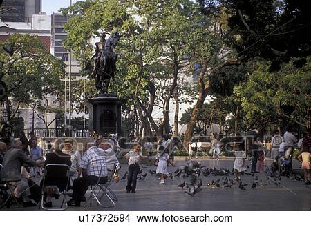 Venezuala, Caracas, South America, Local men sitting in a circle talking while children enjoy a day in Plaza Bolivar in Caracas the capital city of the country of Venezuela. View Large Photo Image Picture - Venezuala, Caracas, South America, Local men sitting in a circle talking while children enjoy a day in Plaza Bolivar in Caracas the capital city of the country of Venezuela.. Fotosearch