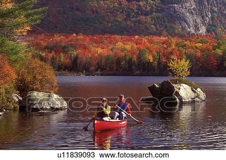 Stock Image -  Vermont, canoe, canoeing, Mother and daughter paddling a red canoe on a fall day on Marshfield Pond in Marshfield. Mad River Canoe Products.. Fotosearch