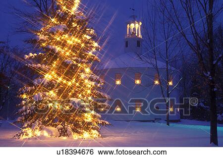 Stock Photograph -  Vermont, Christmas, church, tree, White star lights decorate an evergreen tree in front of the historic Old Round Church at night in Richmond. Christmas candles burn in the windows of the church.. Fotosearch