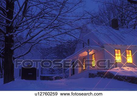 Stock Photo -  Vermont, Christmas, Peacham, Yellow Christmas candles glow in the windows of a country home on a snow covered [night, evening] in Peacham.. Fotosearch