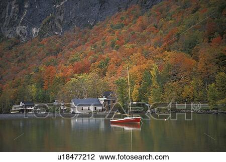 Stock Image -  Vermont, fall, foliage, boat, Lake Willoughby, Westmore, Colorful fall foliage and a red sailboat reflect in the calm waters of Lake Willoughby in Orleans County in the state of Vermont.. Fotosearch