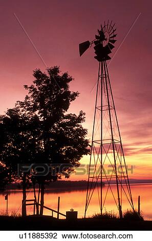 Stock Image -  Vermont, windmill, The silhouette of a windmill at [sunrise, sunset] over Keeler Bay on Lake Champlain in South Hero.. Fotosearch