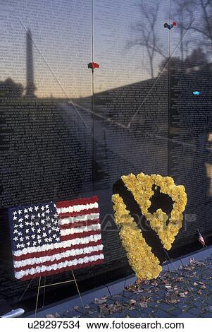 Picture -  Vietnam Veterans Memorial Wall, Washington, DC, District of Columbia, The Washington Monument reflects into the V-shaped black granite wall of the Vietnam Veterans Memorial in Washington, D. C. Wreaths are placed to honor the dead.. Fotosearch