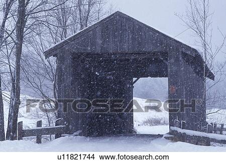 Picture -  winter, covered bridge, Vermont, Snow falls on Scribner or Mudget Covered Bridge on a snowy wintry in Johnson in Lamoille County in the state of Vermont.. Fotosearch