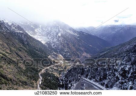 Stock Image -  Andorra, The Pyrenees, Europe, Fog and clouds cover the snow capped Pyrenees Mountains. Scenic view of the valley below.. Fotosearch