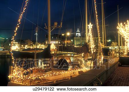 Stock Image -  Annapolis, MD, Maryland, Sailboat decorated with lights for the Christmas holidays at City Dock in downtown Annapolis at night.. Fotosearch