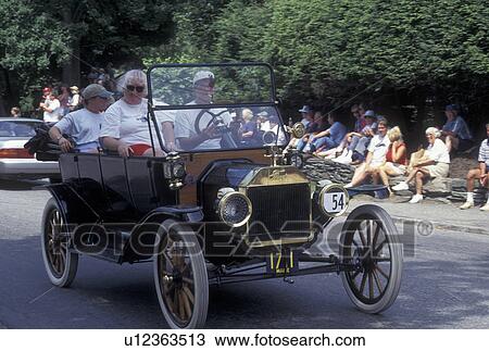 Stock Image -  antique car, Vermont, VT, People riding in an antique car in the Antique & Classic Car Meet Parade in Stowe.. Fotosearch