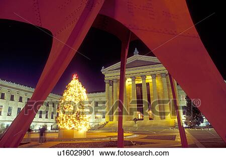 Stock Image -  art museum, Philadelphia, Pennsylvania, PA, Red Calder sculpture and Christmas tree illuminated at night outside the Philadelphia Museum of Art in downtown Philadelphia.. Fotosearch