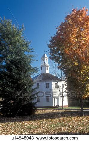Stock Image -  autumn, round church, Vermont, Colorful fall foliage surround the white Old Round Church National Historic Landmark in the fall in Richmond in Chittenden County in the state of Vermont. Thr Round Church is 16-sided polygon that appears round.. Fotosearch