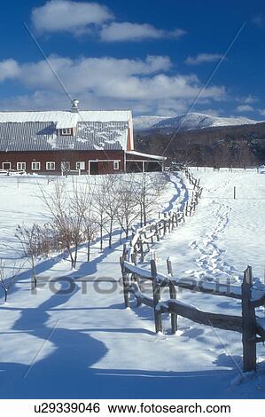 Stock Photograph -  barn, winter scene, snow, Vermont, A split rail fence casting shadows on the snow leads to a red barn on a sunny day in winter in Jericho in Chittenden County in the state of Vermont. . Fotosearch