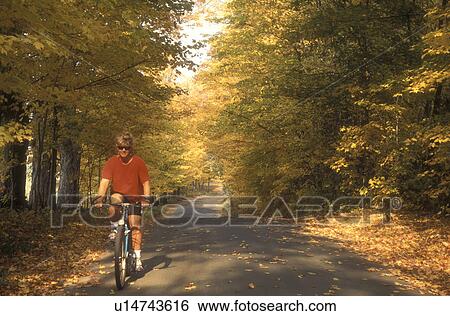 biking, woman, country road, fall, East Montpelier, VT, Vermont, Woman biking on a country road surrounded by colorful fall foliage in East Montpelier in the autumn. View Large Photo Image Stock Photograph - biking, woman, country road, fall, East Montpelier, VT, Vermont, Woman biking on a country road surrounded by colorful fall foliage in East Montpelier in the autumn.. Fotosearch