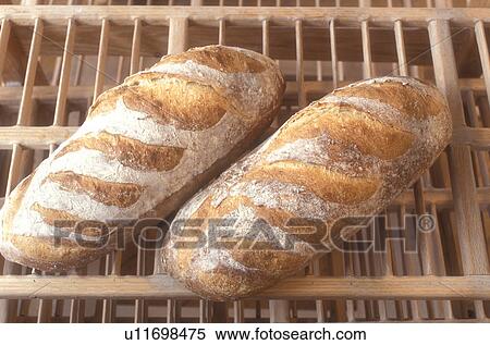 Stock Photography -  bread, bakery, loaf, French bread, fresh, close-up, Two freshly baked country loaves are displayed on the wooden cooling racks at Gerard's Bakery in Westford in the state of Vermont. . Fotosearch