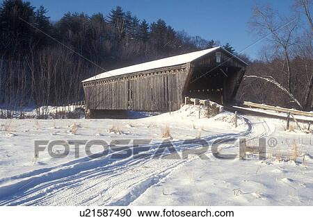 Stock Image -  bridge, covered bridge, winter, Scenic view of Gorham or Goodnaugh Covered Bridge ca. 1841 and snowmobile tracks on a sunny day in winter in Pittsford in Rutland County in the state of Vermont. . Fotosearch