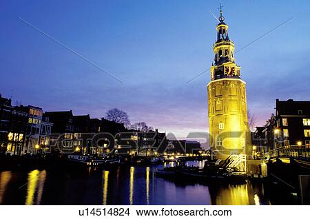 Picture -  canal, Amsterdam, Holland, The Netherlands, Europe, The clock tower is illuminated at night along the canal (grachten) in downtown Amsterdam. . Fotosearch