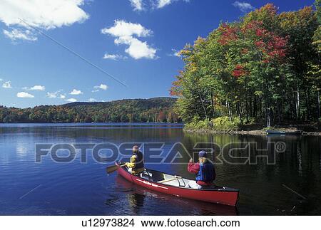 Picture -  canoe, canoeing, Vermont, VT, Mother and daughter paddle a red canoe on Green River Reservoir in Hyde Park in the fall. . Fotosearch