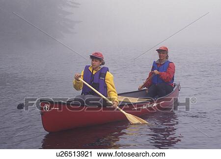 Stock Image -  canoe, canoeing, Vermont, VT, Mother and daughter paddle a red canoe in the fog on Kettle Pond in Groton State Forest.. Fotosearch