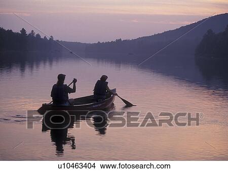 Picture -  canoeing, canoe, sunrise, sunset, Vermont, VT, Mother and daughter paddle a canoe at sunset on Kettle Pond in Groton State Forest.. Fotosearch