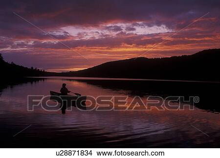 canoeing, canoe, sunrise, sunset, Vermont, VT, Silhouette of a woman paddling a canoe on Kettle Pond at sunset in Groton State Forest. View Large Photo Image Picture - canoeing, canoe, sunrise, sunset, Vermont, VT, Silhouette of a woman paddling a canoe on Kettle Pond at sunset in Groton State Forest.. Fotosearch