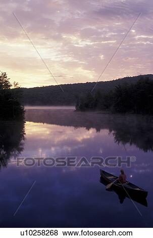 Stock Photo -  canoeing, canoe, sunrise, sunset, Vermont, VT, Woman canoeing on Green River Reservoir at sunrise in Hyde Park. . Fotosearch