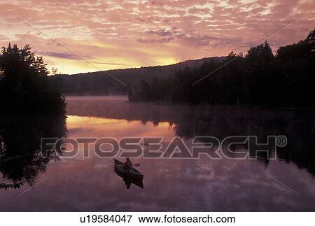 Stock Photo -  canoeing, canoe, sunrise, sunset, Vermont, VT, Woman canoeing on Green River Reservoir at sunrise in Hyde Park. . Fotosearch