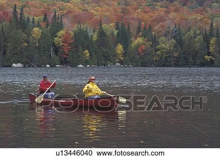 Stock Image -  canoeing, canoe, Vermont, VT, Mother and daughter paddling a red canoe on Jobs Pond in Westmore in the fall. . Fotosearch
