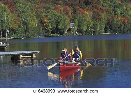 Stock Image -  canoeing, canoe, Vermont, VT, Mother and daughter paddle a red canoe on Long Pond in Westmore in the fall surrounded by colorful foliage. . Fotosearch