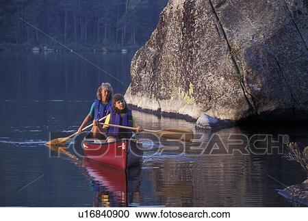 Stock Image -  canoeing, canoe, Vermont, VT, Mother and daughter paddling a red canoe next to a boulder on Kettle Pond in Groton State Forest.. Fotosearch