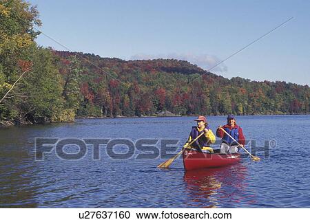Stock Image -  canoeing, canoe, Vermont, VT, Mother and daughter paddling a red canoe on Green River Reservoir in Hyde Park in the fall. . Fotosearch