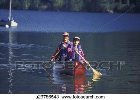 Stock Image -  canoeing, canoe, Vermont, VT, Mother and daughter paddling a red canoe on Lake Willoughby in Westmore. Fotosearch