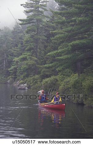 Stock Photo -  canoeing, canoe, Vermont, VT, Mother and daughter paddle a red canoe on Kettle Pond in Groton State Forest.. Fotosearch