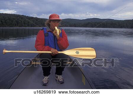 canoeing, canoe, Vermont, VT, Woman eating a banana while sitting in a red canoe on Green River Reservoir in Hyde Park. View Large Photo Image Stock Photo - canoeing, canoe, Vermont, VT, Woman eating a banana while sitting in a red canoe on Green River Reservoir in Hyde Park. . Fotosearch