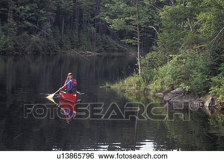 Stock Photograph -  canoeing, canoe, Vermont, VT, Woman paddling a red canoe on Green River Reservoir in Hyde Park. . Fotosearch