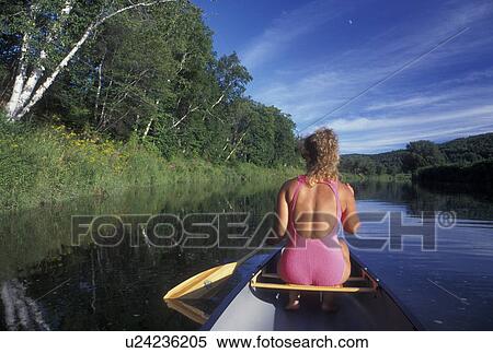 Stock Photography -  canoeing, canoe, Vermont, VT, Woman paddling a red canoe on the Winooski River in Middlesex.. Fotosearch