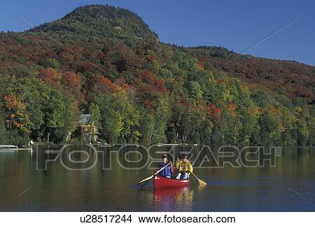 Picture -  canoeing, Vermont, VT, Mother and daughter paddle a red canoe on Long Pond in Westmore in the fall surrounded by colorful foliage. . Fotosearch
