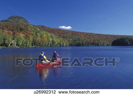 Stock Image -  canoeing, Vermont, VT, Mother and daughter paddle a red canoe on Long Pond in Westmore in the fall. . Fotosearch