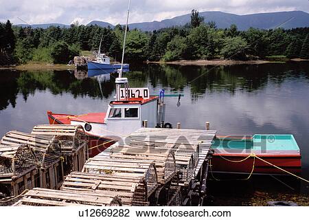 Stock Image -  Cape Breton, Nova Scotia, NS, Canada, Red and blue lobster boats in Dingwall in Cape Breton. Lobster traps on dock.. Fotosearch