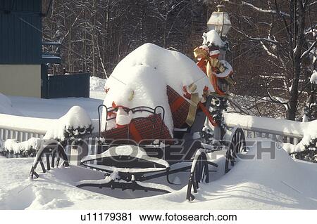 Stock Image -  carriage, decorations, Christmas, holiday, gift, ribbon, snow, winter, A snow covered antique carriage is decorated with gifts and bows for the Christmas holiday season in Shelburne in Rutland County in the state of Vermont. . Fotosearch