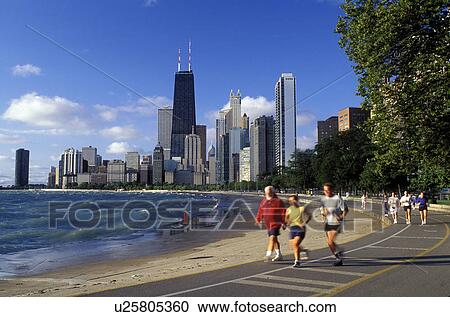 Stock Image -  Chicago, skyline, Illinois, IL, Lake Michigan, People jogging on the recreational path at Lake Shore Park on Lake Michigan with the view of the downtown skyline of Chicago in the background.. Fotosearch